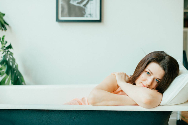 young pretty woman lying in empty vintage cast-iron bath - Foto, Imagen