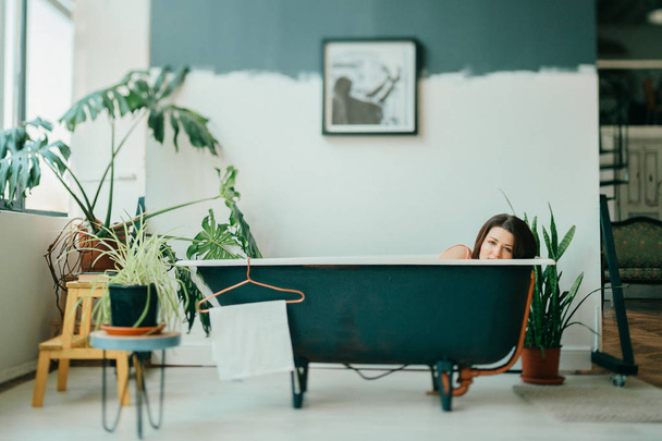 young pretty woman lying in empty vintage cast-iron bath - Fotó, kép