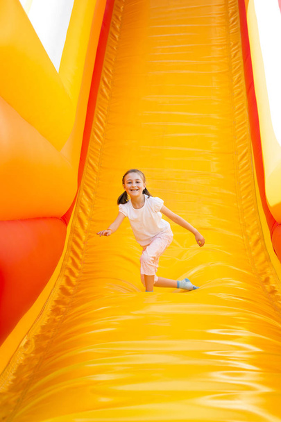 Felice bambina avendo un sacco di divertimento su un castello di salto durante lo scorrimento
. - Foto, immagini