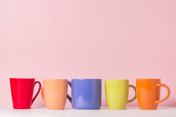 ピンクの背景でコーヒーまたは紅茶の色とりどりのカップがたくさん。フレンドリーな会社、大家族、紅茶やコーヒーのカップのための会合の友人の概念 - 写真・画像