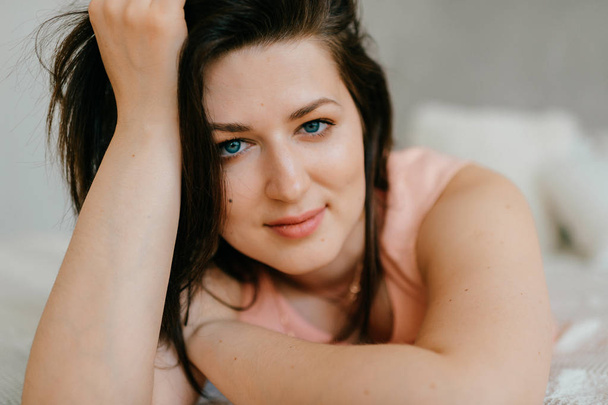 Beautiful brunette woman lying on white bed at home in morning - Fotografie, Obrázek