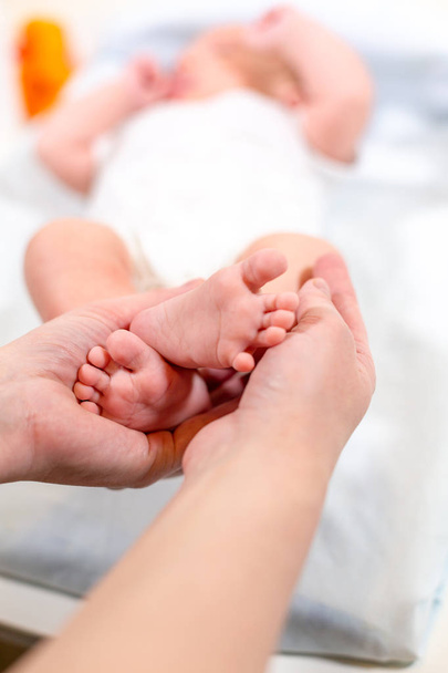 Baby feet in mother hands. Tiny Newborn Babys feet on female Shaped hands closeup. Mom and her Child. Happy Family concept. Beautiful conceptual image of Maternity - Foto, Bild