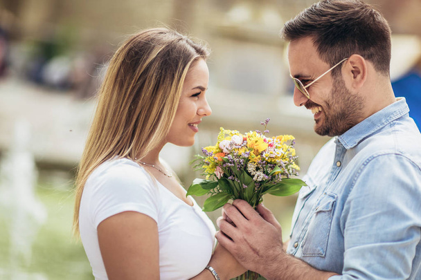 Picture of young man surprising woman with flowers - Fotografie, Obrázek