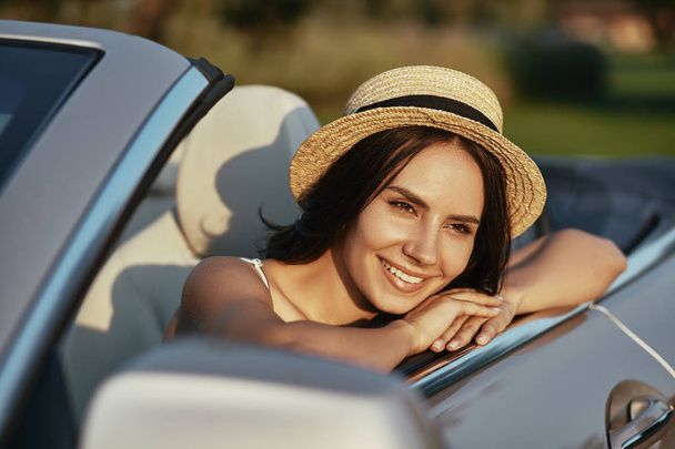 happy young woman in the summer hat sitting in cabrio and looking away - Zdjęcie, obraz