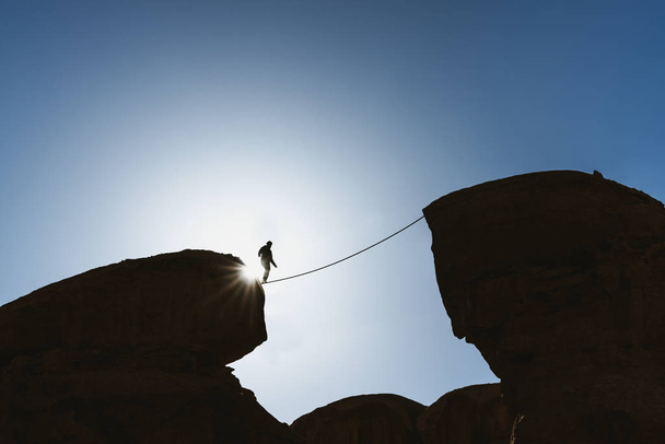un homme marchant sur une corde au-dessus d'un précipice. Affaires, prise de risques, défi, bravoure et concentration
 - Photo, image