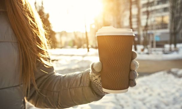 Young woman holds cup of coffee takeaway in the winter park - Foto, Imagem