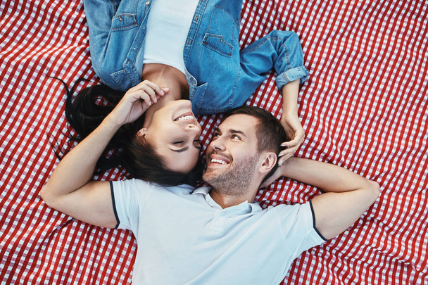 overhead view of smiling couple laying on the colorful blanket face to face - Photo, image