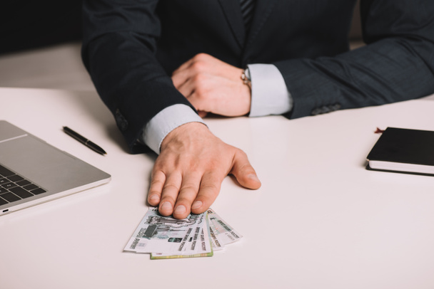 abgeschnittene Aufnahme eines Geschäftsmannes, der russische Rubel-Banknoten auf dem Tisch hält - Foto, Bild