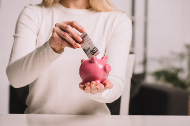 cropped shot of woman putting russian rubles into piggy bank, savings concept  - Photo, Image