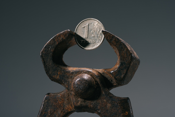 close-up view of iron vise tool with one ruble coin isolated on grey - Photo, Image