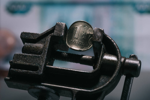 Nahaufnahme des Schraubstock-Werkzeugs mit einer Rubel-Münze, selektiver Fokus - Foto, Bild