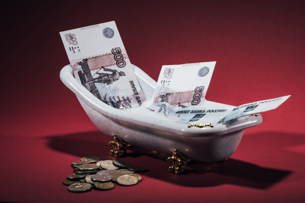 russian rubles banknotes in small tub and coins on red, money laundering concept - 写真・画像