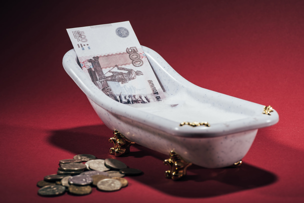 close-up view of russian rubles in small tub and coins on red, money laundering concept - Foto, Bild