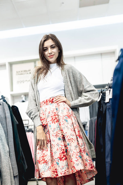 young beautiful emotional modern woman walks through the shopping center, looks at fashion things in clothing stores - 写真・画像