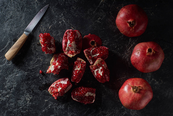 Top view of ripe pomegranates and knife on textured surface - Photo, image