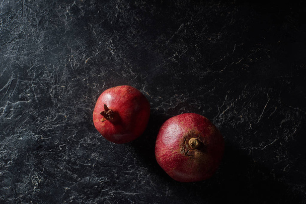 Top view of two ripe garnets on black surface - 写真・画像