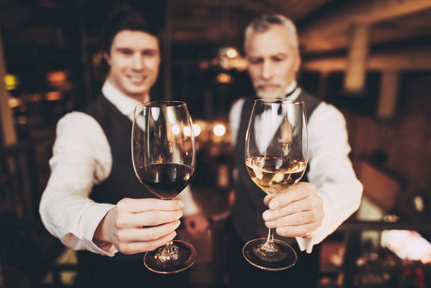 Genç ve yaşlı sommeliers bardak kırmızı ve beyaz şarap restoranda tutuyor. - Fotoğraf, Görsel