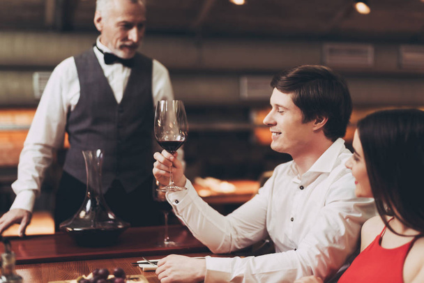 Young happy man is holding glass of wine. Sommelier recommends wine for couple. - Fotoğraf, Görsel