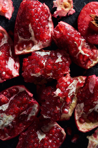 Top view of fresh cut pomegranates on black surface - Foto, afbeelding