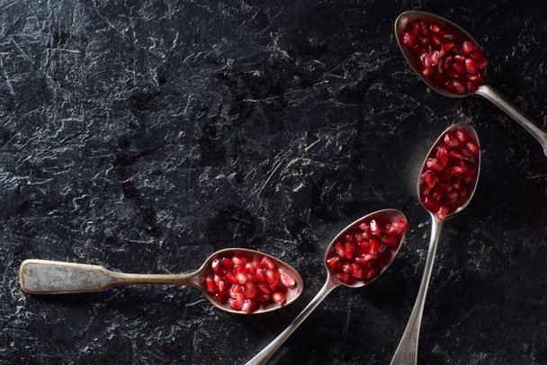 Flat lay with spoons of garnet seeds on textured background - Photo, Image