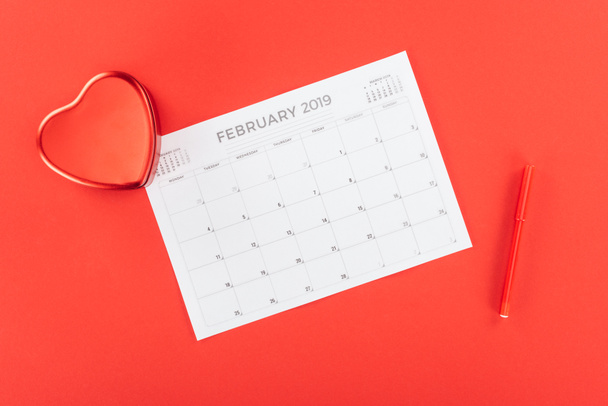 top view of heart shaped box and february 2019 calendar isolated on red, st valentines day concept - Photo, Image