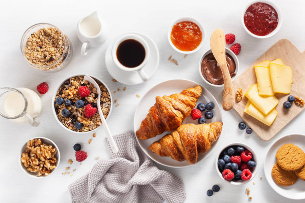 Zdravá snídaně s cereáliemi, bobule, ořechy, croissant, jam, čokoládová pomazánka a kávu. Pohled shora - Fotografie, Obrázek