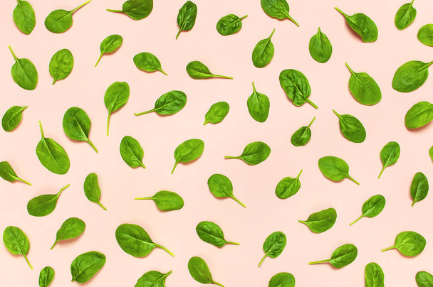 ピンク背景フラットに新鮮な緑のほうれん草の葉模様には、上面が横たわっていた。創作料理のコンセプトです。サラダのための成分。野菜模様。健康的なライフ スタイル - 写真・画像