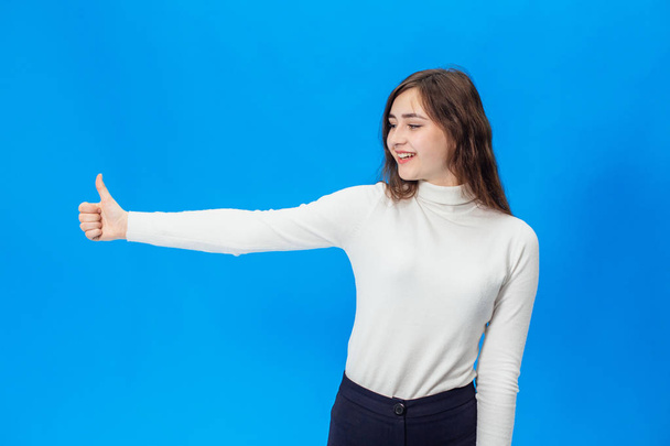 Young woman on a blue background. A girl on a blue background with smile - Foto, afbeelding