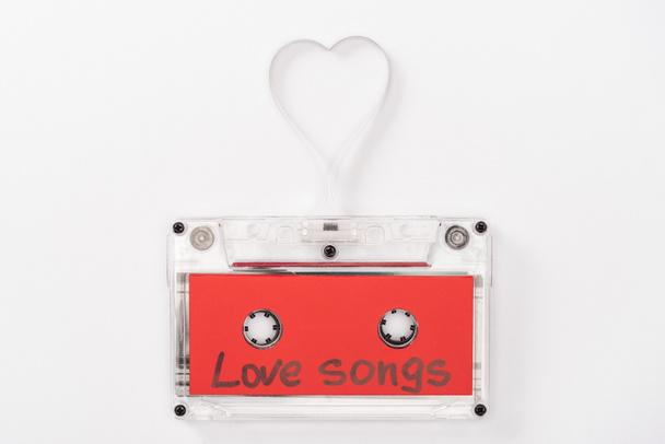 top view of audio cassette with 'love songs' lettering and heart symbol isolated on white, st valentines day concept - Zdjęcie, obraz