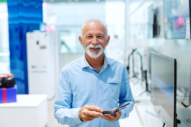 Portrét starého vousatý muž držící brožura a při pohledu na fotoaparát stoje v tech úložišti. - Fotografie, Obrázek
