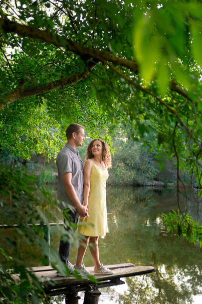 Pareja enamorada en el lago, hora de verano. Árboles verdes y lago, pareja familiar, amor y romanticismo. Concepto de relación, felicidad, unión
. - Foto, imagen