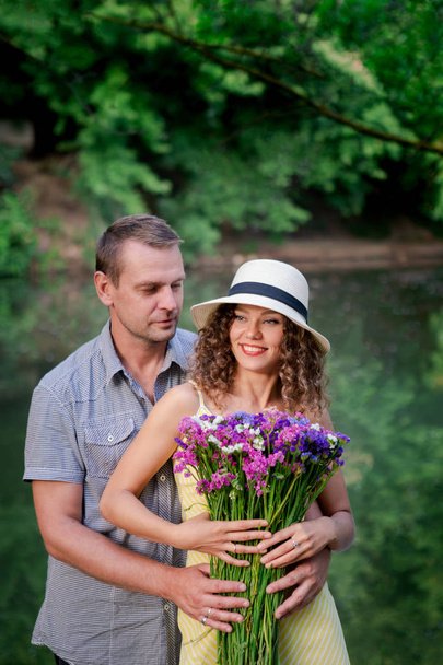 Couple in love, happy woman with flowers, summer time. Green trees outdoor, family couple, love and romantic. Concept of relationship, happiness, togetherness. - 写真・画像