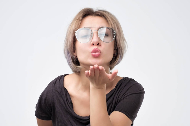 Beautiful woman wearing summer glasses sending an air kiss - Foto, afbeelding