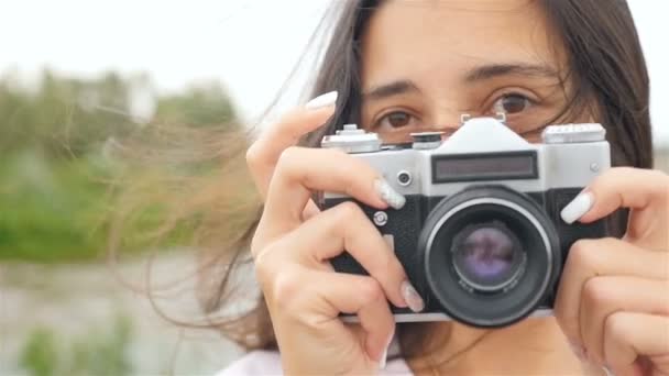 Una hermosa chica sostiene una cámara y toma fotos. Primer plano
 - Metraje, vídeo