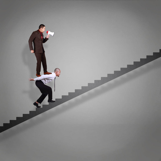 Businessman walking on stairs up fprwards while carrying his boss on his back, bad leader shout with megaphone, failure adversity in business concept - Photo, Image