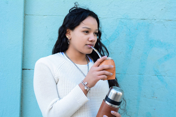 Portrait of Young latin woman drinking traditional Argentinian yerba mate tea. South american popular drink. Outdoors - Foto, Imagen
