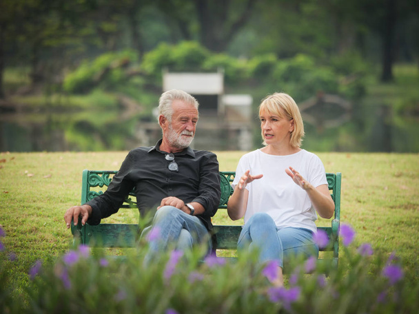 Two happy seniors retirement Man and woman are sitting and talking in park - Foto, imagen