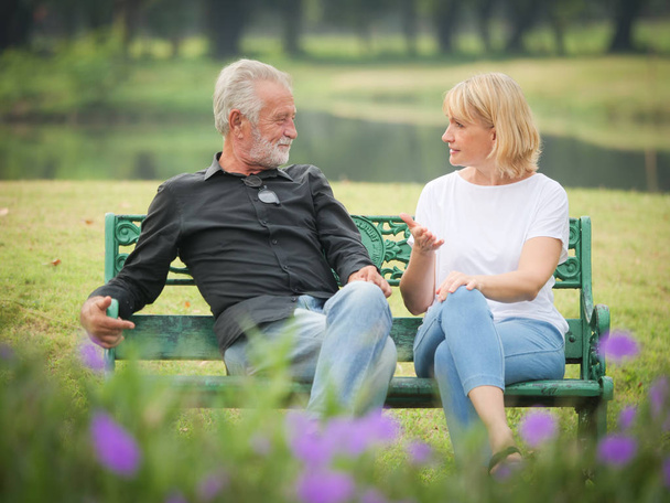 Two happy seniors retirement Man and woman are sitting and talking in park - Photo, Image