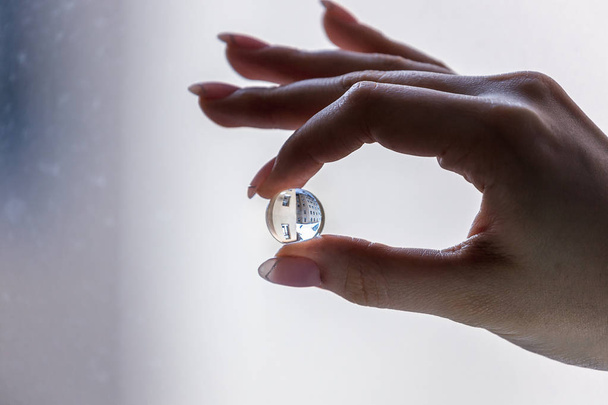 small growimg water ball in fingers, orbiz  and house in it, up and down image, transparent ball - Photo, Image