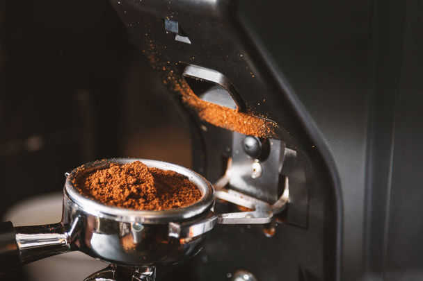 Barista grinding coffee beans using coffee machine, coffee grinder grinding freshly roasted make beans into a powder. - Zdjęcie, obraz
