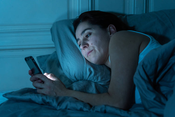 Addicted nuori kaunis nainen chattailuun ja surffailuun internetissä käyttämällä hänen älypuhelin unelias tylsää ja väsynyt myöhään yöllä Internet, Mobile riippuvuus ja unettomuus käsite
. - Valokuva, kuva