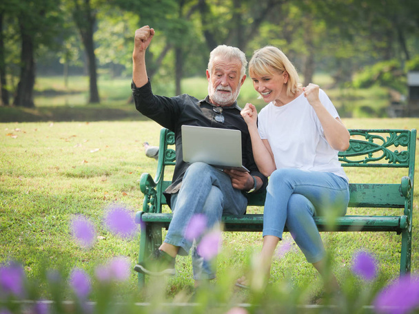 Two happy seniors retirement Man and woman are sitting and using computer laptop in park - Foto, Bild