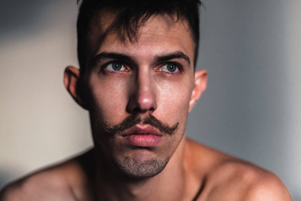 Young shirtless man with mustache thinking by the window - Photo, Image