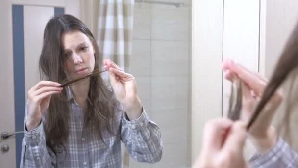 Woman looks at her dry, brittle hair in the bathroom. - Filmati, video