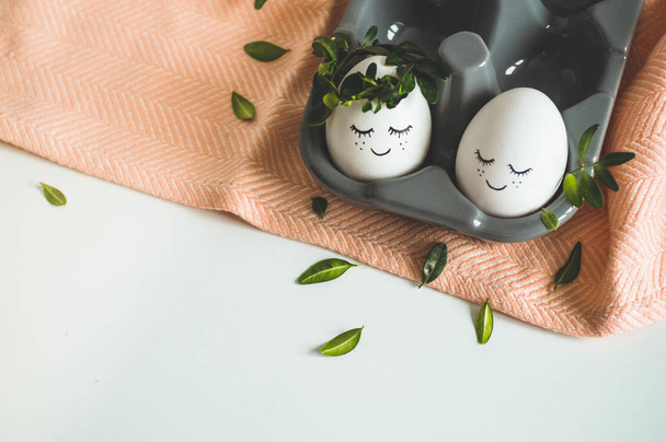 Ευτυχισμένο Πάσχα κάρτα. Χαριτωμένα Πασχαλινά αυγά με βαμμένο πρόσωπο σε ένα στεφάνι άνοιξη με αντίγραφο χώρο για το κείμενο. Καλό Πάσχα.  - Φωτογραφία, εικόνα