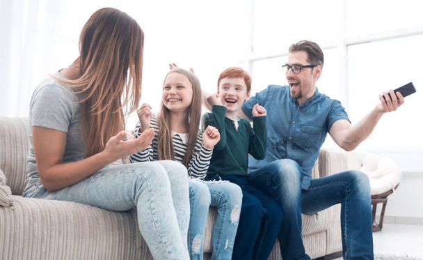 happy family sitting watching TV in their home - Fotó, kép