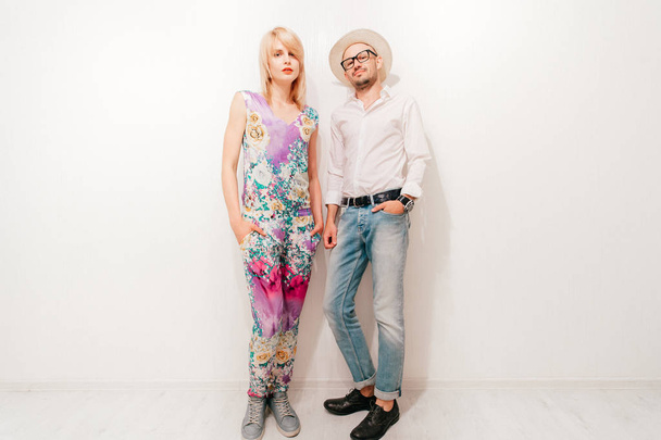 fashionable couple in trendy clothes standing at white wall at home - Fotó, kép
