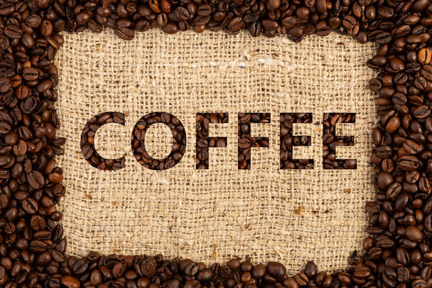 Granos asados deletreo café en el marco en el fondo de la bolsa de tela marrón
 - Foto, Imagen