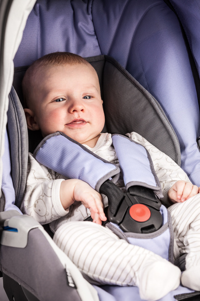 Aranyos kisfiú visel egy helyet a gyermek autósülés - Fotó, kép