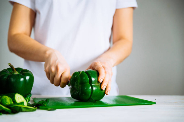 женщина режет зеленую бумагу на зеленой доске кухни
 - Фото, изображение